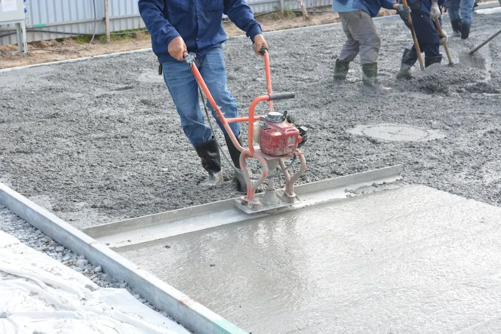Freshly poured reinforced concrete slab being levelled by the crew